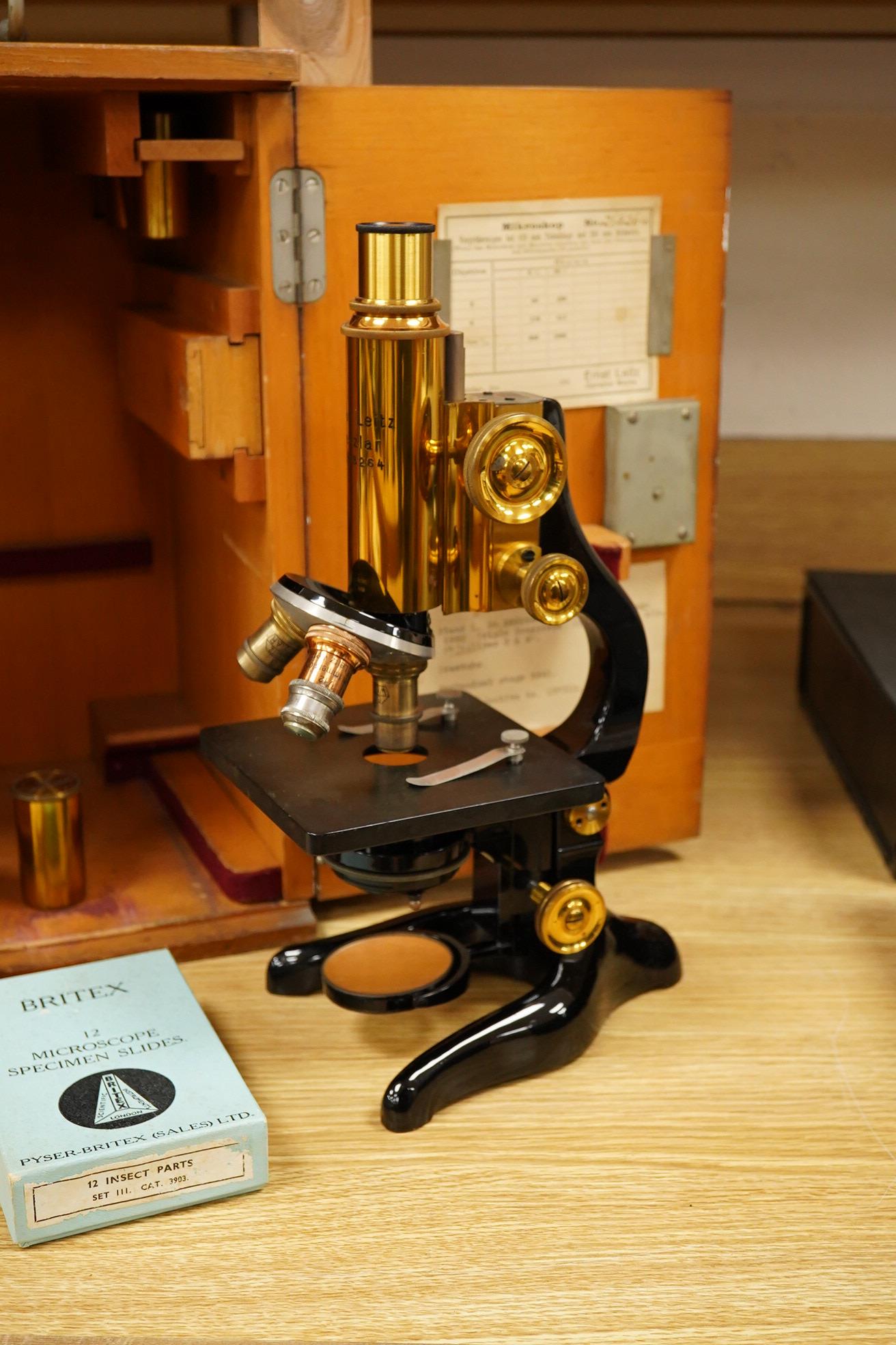 An early 20th century teak cased Ernst Leitz, Wetzlar brass and cast iron monocular microscope, serial no. 268264, with fitted interior to the case and card box of specimen slides, case dimensions; 36cm high, 19cm wide,